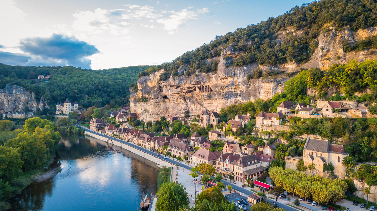 La Roque-Gageac, pintoresco pueblo ribereño del suroeste de Francia, encajado bajo grandes acantilados de piedra caliza y reflejado en las aguas tranquilas del río.