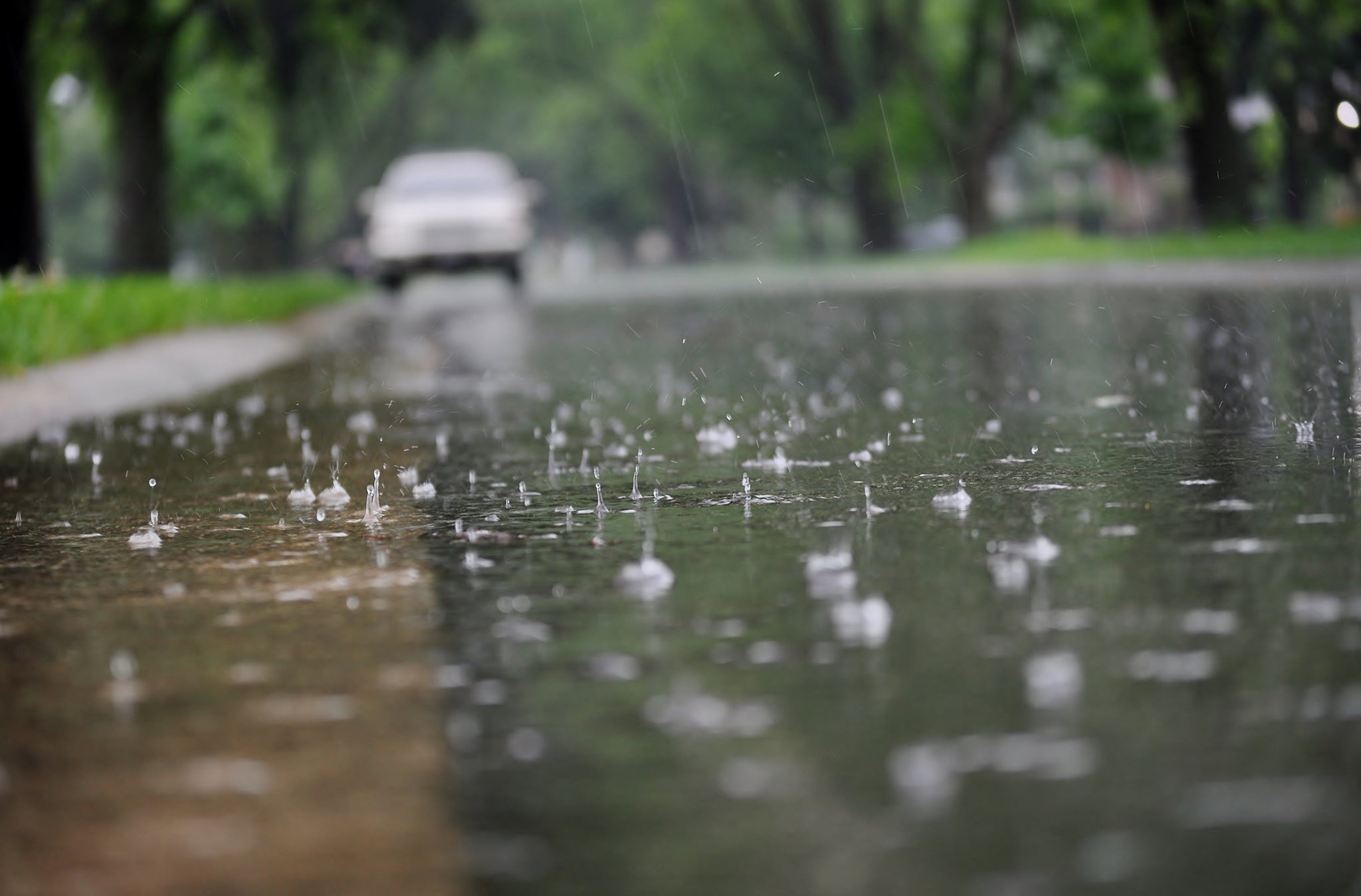 Water flowing along the street curb during heavy rain. Close up of splashing raindrops and air bubbles.